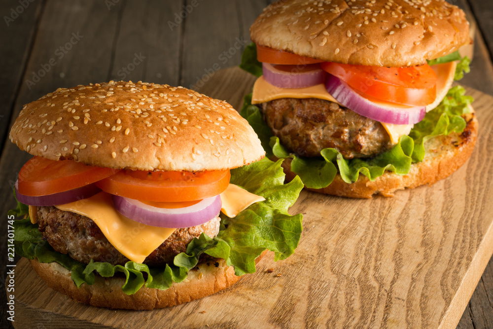 Home made hamburger with beef, onion, tomato, lettuce and cheese. Fresh burger close up on wooden rustic table with potato fries, beer and chips. Cheeseburger. Home made hamburger with beef, onion, tomato, lettuce and cheese. Fresh burger close up on wooden rustic table with potato fries, beer and chips. Cheeseburger.