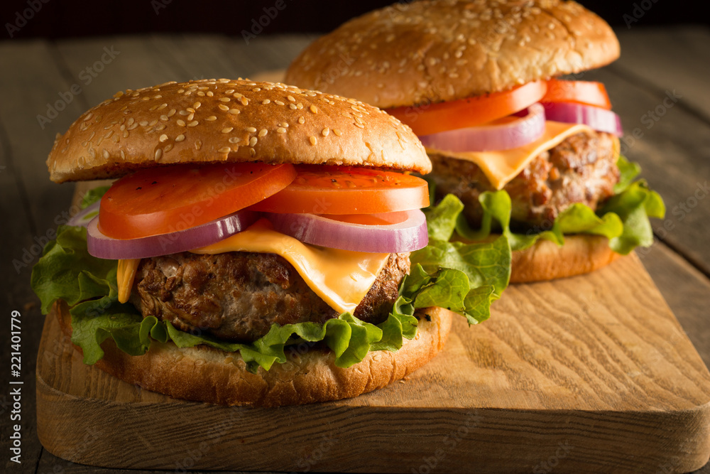 Home made hamburger with beef, onion, tomato, lettuce and cheese. Fresh burger close up on wooden rustic table with potato fries, beer and chips. Cheeseburger. Home made hamburger with beef, onion, tomato, lettuce and cheese. Fresh burger close up on wooden rustic table with potato fries, beer and chips. Cheeseburger.