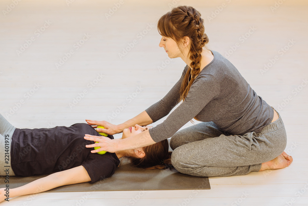 Woman instructor massaging female patient with technique applying two tennis balls. Treatment pain concept . Practical use.