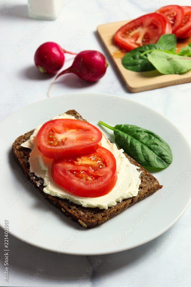 Dense rye bread with creamy cheese and tomato slices Dense rye bread with creamy cheese and tomato slices