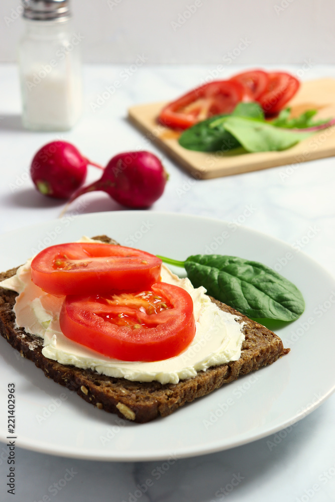 Dense rye bread with creamy cheese and tomato slices Dense rye bread with creamy cheese and tomato slices
