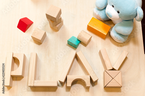 Child or baby play set, toy wooden blocks, teddy bear. Kindergarten or preschool background.