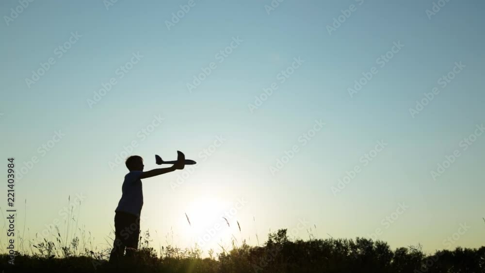 custom made wallpaper toronto digitalOne little happy kid playing with toy airplane in park on sunset time. Black silhouette of child isolated on blue sky background. Outdoor games and fun concept. Real time full hd video footage.