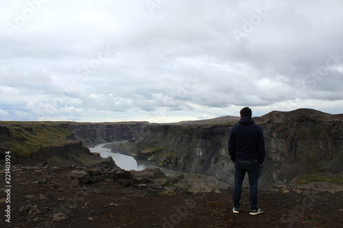 Man standing and overlooking a waterfall canyon in Iceland