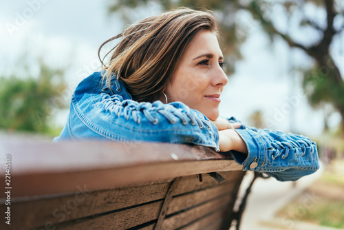 Young woman sitting on a bench daydreaming photo