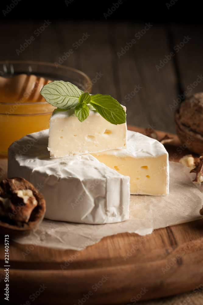 Camembert and brie cheese on wooden background with tomatoes, letuce and garlic. Italian food. Dairy products. Camembert and brie cheese on wooden background with tomatoes, letuce and garlic. Italian food. Dairy products.