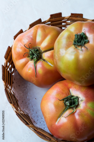 Pink Organic Big Tomatoes in Wooden Basket. photo