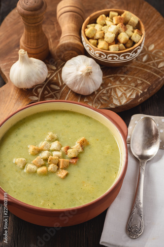 Broccoli cream soup with croutons on wooden background.