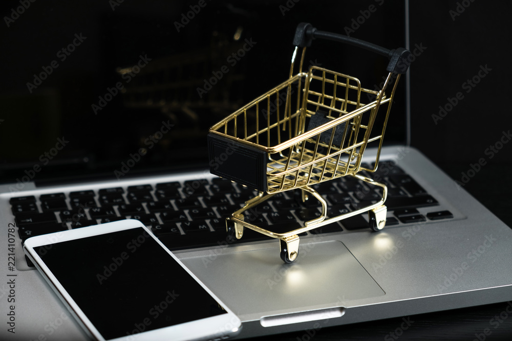 Gold cart, cash and gadgets on a black table.