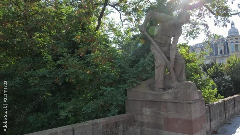 Strasbourg France: August 2018. A statue of a shoveler on John F. Kennedy bridge build in 1906 in Strasbourg. Four statues keep watch over the bridge entrances. These sculptures symbolize the river Strasbourg France: August 2018. A statue of a shoveler on John F. Kennedy bridge build in 1906 in Strasbourg. Four statues keep watch over the bridge entrances. These sculptures symbolize the river
