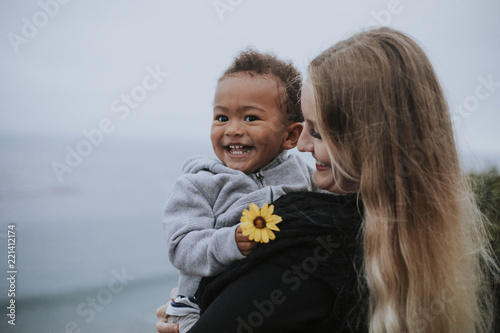 Canvastavla Young boy holding a flower carried by his mom
