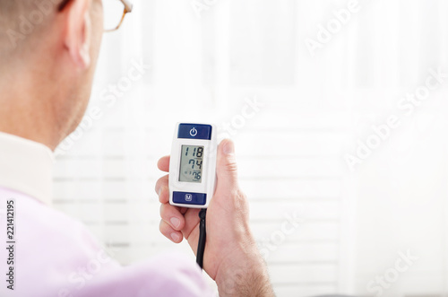 Man read measurement results from personal digital blood pressure monitor