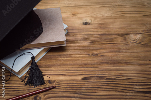 Graduate cap, stack of books and school pointer on the wooden school desk with copy space. photo
