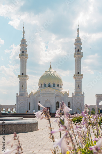 The white mosque against the sky and flowers.