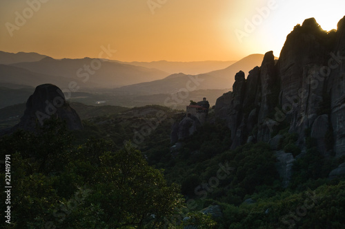 Huge rocks with monasteries and sunset behind distant mountains in Meteora, Thessaly, Greece