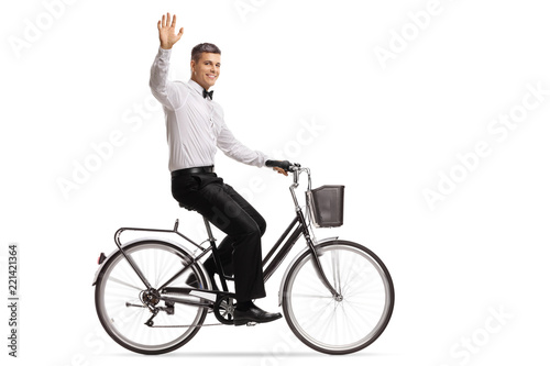 Groom riding a bicycle and waving at the camera
