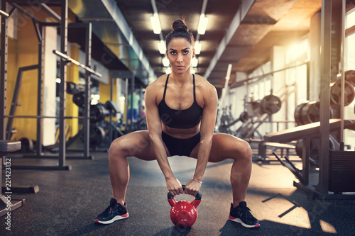 Female doing squats using kettle bell weight