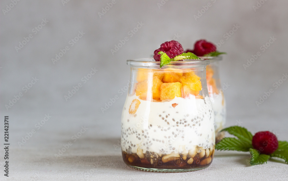Vanilla chia seeds pudding in glasses with fresh raspberries and peaches. Healthy dessert breakfast.