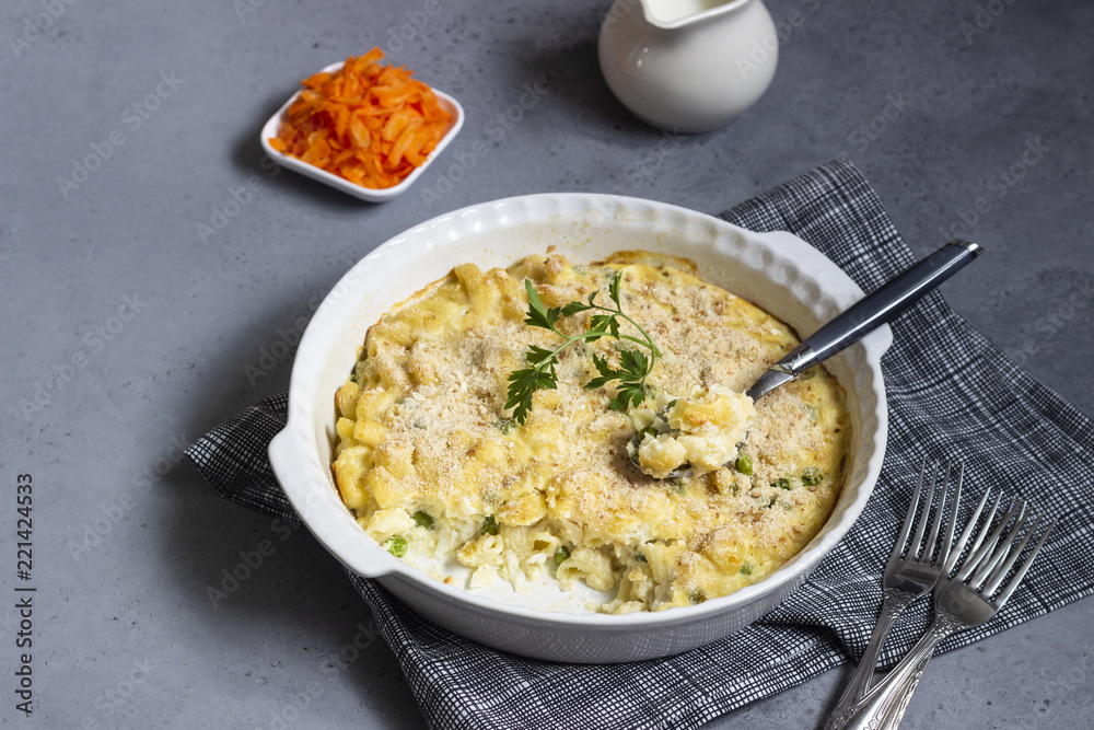 Homemade pasta casserole with fish and green pea in bechamel sauce in a baking dish on a light slate, stone or concrete background. Copy space for text. Homemade pasta casserole with fish and green pea in bechamel sauce in a baking dish on a light slate, stone or concrete background. Copy space for text.
