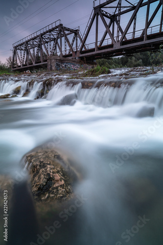 View on the river with water fall and train bridge photo