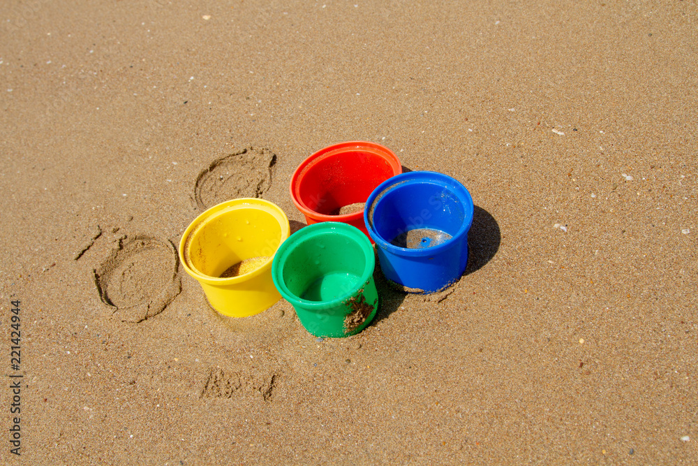 Bright children's molds for the pyramids on the wet beach sand. Bright children's toys in the sea. Toys for little children on the beach. Close-up. Bright children's molds for the pyramids on the wet beach sand. Bright children's toys in the sea. Toys for little children on the beach. Close-up.