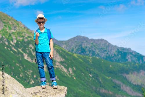 happy little traveler with a backpack in the background of the mountains