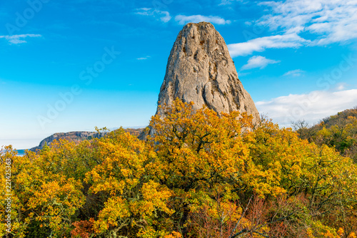 High rock surrounded by a yellow autumn forest in the mountains of Crimea, picturesque landscape