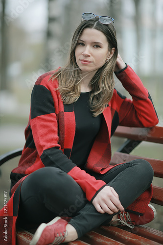girl is sitting on a garden bench / beautiful model posing sitting in  coat on  bench in  city park, beautiful girl © kichigin19