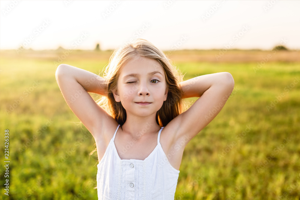 adorable little child winking at camera on green field under sunset rays adorable little child winking at camera on green field under sunset rays
