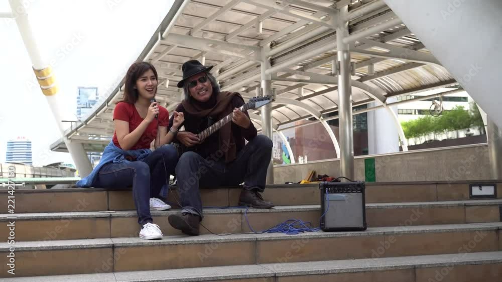 Street musician duo of female singer and male guitarist performing on the street Street musician duo of female singer and male guitarist performing on the street
