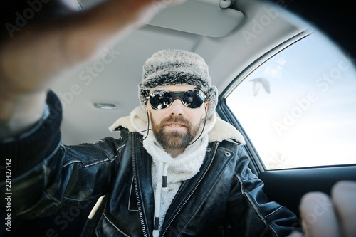 driver of the car in winter clothes, man behind the wheel, a winter journey on car, brutal man with beard on the car, professional traveler