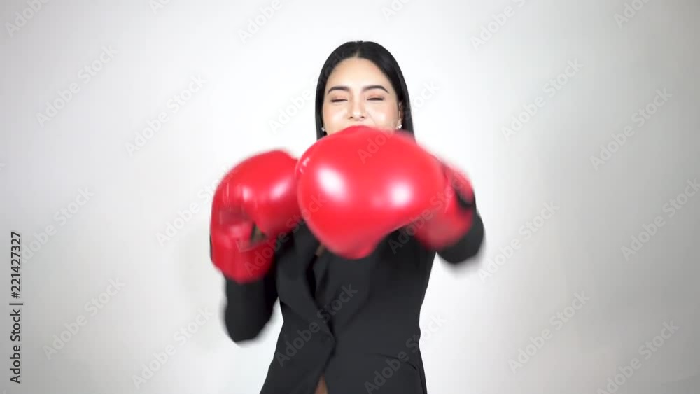 Young happy and energetic business woman keeps punching and raising hands with boxing gloves on white background Young happy and energetic business woman keeps punching and raising hands with boxing gloves on white background
