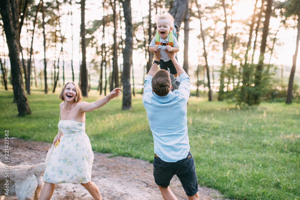Obraz premium A cute family - mom, dad and son spend fun time outdoors with their dog