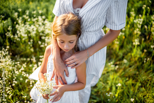 cropped shot of mother and daughter with field flowers bouquet embracing in green meadow