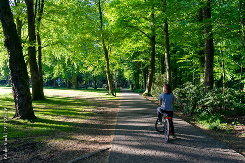 Jovem montada em bicicleta num passeio no meio de um parque