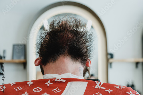 Handsome bearded man in barbershop. Barber brushes and cuts hair with trimmer. photo