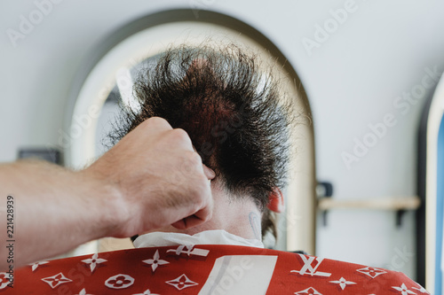 Handsome bearded man in barbershop. Barber brushes and cuts hair with trimmer. photo