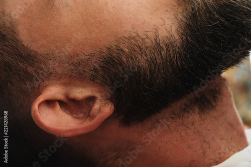 Handsome bearded man in barbershop. Barber brushes and cuts hair with trimmer. photo