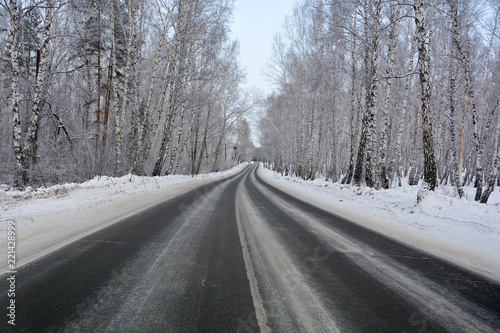 Snowy winter road in pine and birch forest.The Northern part of Russia 
