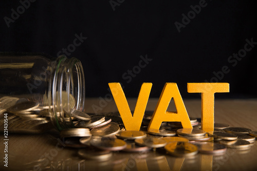 Vat Concept.Word vat put on coins and glass bottles with coins inside on black background. photo