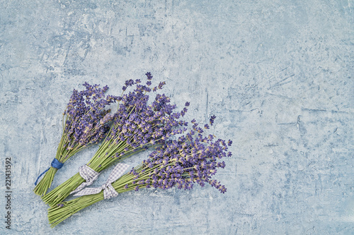 Fototapeta Naklejka Na Ścianę i Meble -  Three bouquet of lavender flowers on blue background. Copy space, top view.