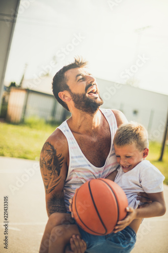 Happy father playing basketball with son.