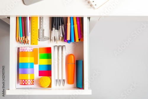 Opened office desk drawer with stationary