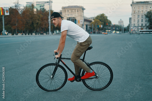 Young modern man cycling on a classic bike on the city road © arthurhidden