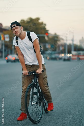 Portrait of young man walking thoughtfully with classic bicycle