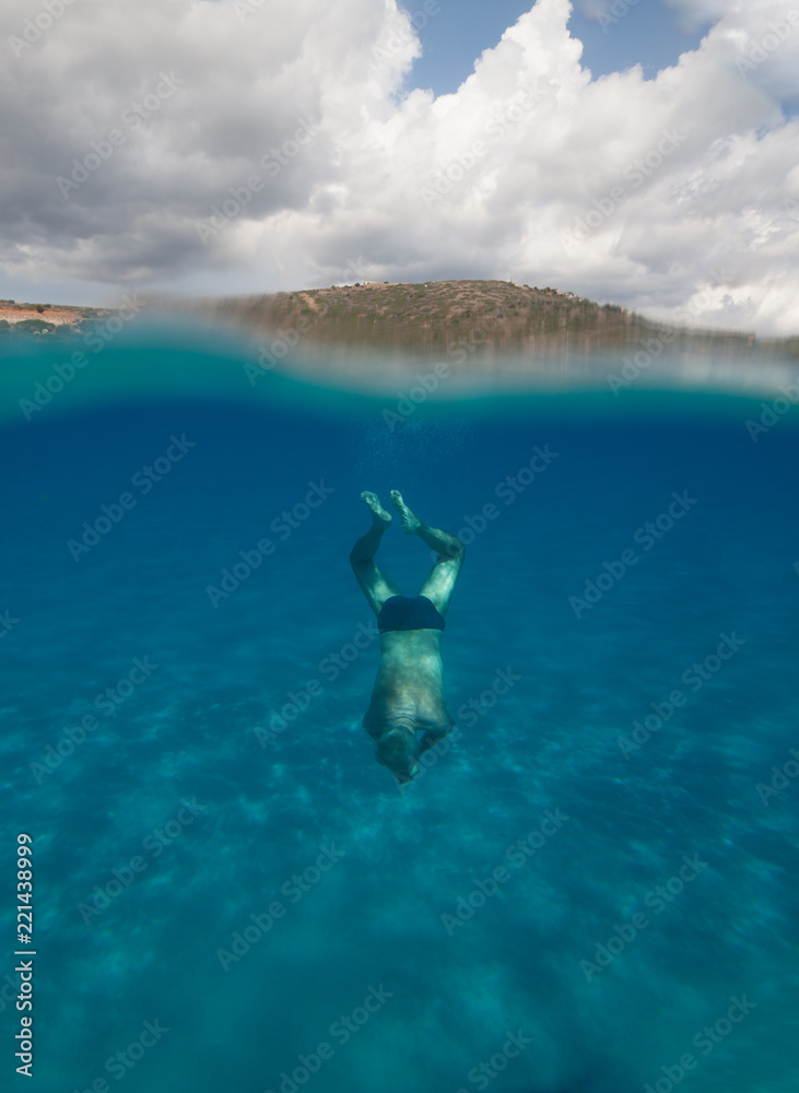 Half underwater view of a senior man with stunning landscape in south Sardinia named Mari Pintau - italy 2