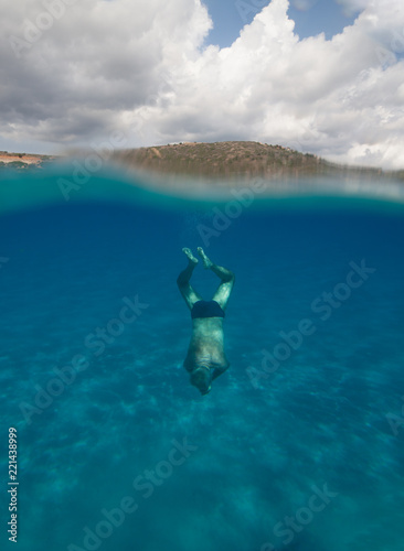 Half underwater view of a senior man with stunning landscape in south Sardinia named Mari Pintau - italy 2