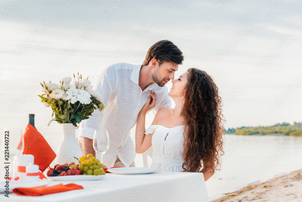 Naklejka premium beautiful couple kissing on romantic date on seashore