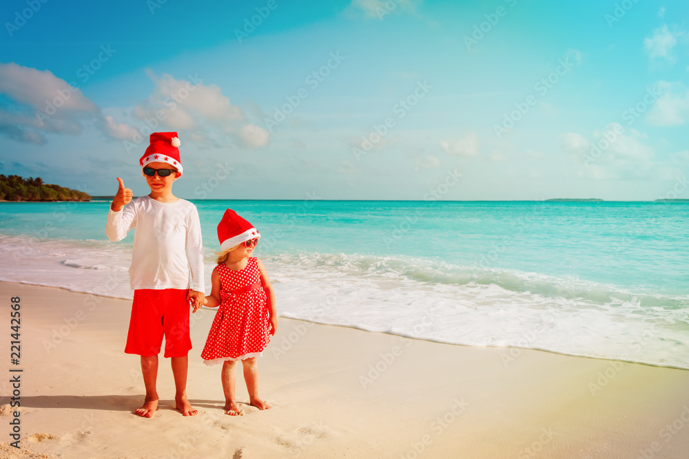 kids- boy and girl- celebrating christmas on tropical beach kids- boy and girl- celebrating christmas on tropical beach