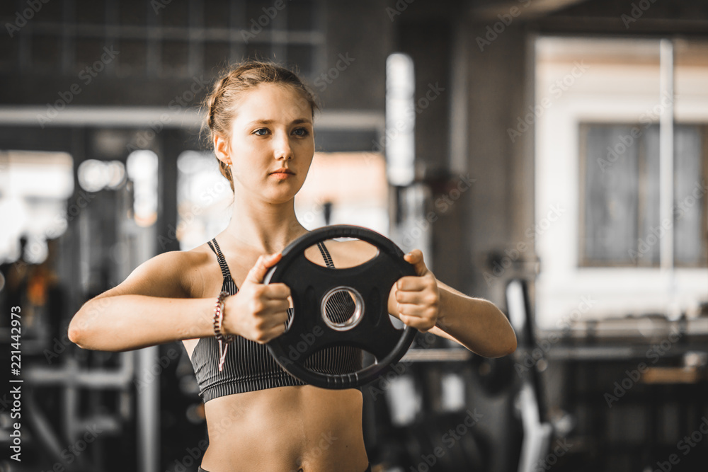 Fit beautiful young woman caucasian posing at the camera in sportswear. Young woman holding dumbbell during an exercise class in a gym. Healthy sports lifestyle, Fitness concept. Fit beautiful young woman caucasian posing at the camera in sportswear. Young woman holding dumbbell during an exercise class in a gym. Healthy sports lifestyle, Fitness concept.